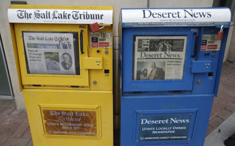 The Salt Lake Tribune and Deseret News,  newspaper boxes are shown next to each other  Monday, June 16, 2014, in Salt Lake City. A group of former employees of The Salt Lake Tribune have filed a lawsuit to suspend the newspaper's joint operating agreement with the Deseret News, arguing that the terms violate federal antitrust laws and undermine the Tribune's independent voice.   (AP Photo/Rick Bowmer)