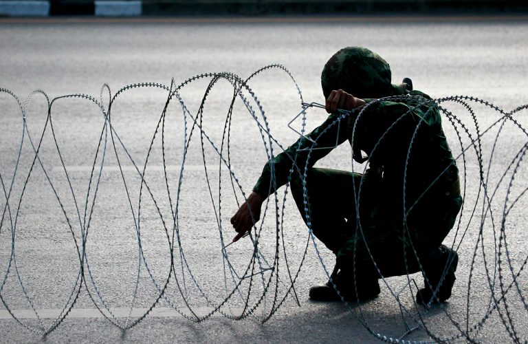 A Thai soldier checks barbed wire while guarding a road near pro-government demonstration site on the outskirts of Bangkok, Thailand Wednesday, May 21, 2014. Thailand's army chief Gen. Prayuth Chan-ocha assumed the role of mediator Wednesday by summoning the country's key political rivals for face-to-face talks one day after imposing martial law. The meeting ended without any resolution, however, underscoring the profound challenge the army faces in trying to end the country's crisis. (AP Photo/Wason Wanichakorn)