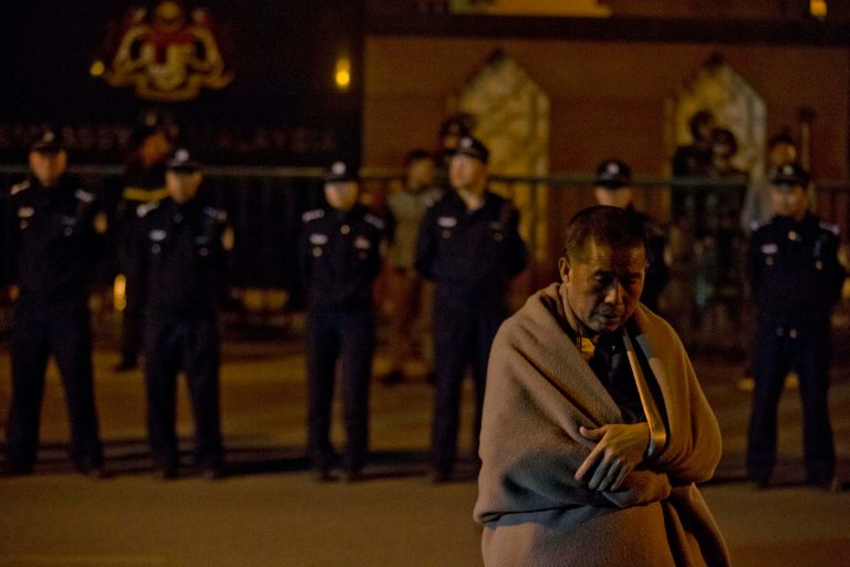 A relative of Chinese passengers onboard the Malaysia Airlines MH370 wrapped in a blanket against the cold, waits for Malaysia embassy staff to meet their demands outside the Malaysia embassy in Beijing, China, Friday, April 25, 2014. Angry relatives who had been waiting for more than 8 hours in vain for a Malaysia embassy representative to attend their daily meeting marched to the Malaysia embassy and protested through the night. (AP Photo/Ng Han Guan)