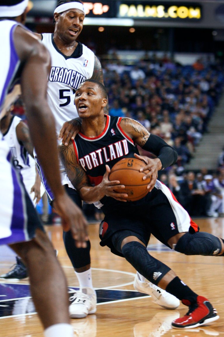   Portland Trail Blazers guard Damian Lillard, right, drives to the basket around Sacramento Kings defender James Johnson during the first half of an NBA basketball game in Sacramento, Calif., on Sunday, Dec. 23, 2012. (AP Photo/Steve Yeater)  