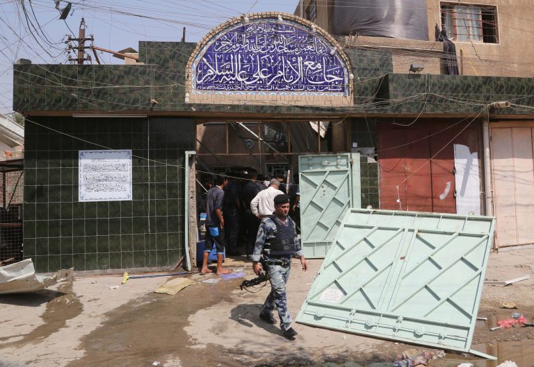 Security forces and civilians inspect the damage outside Imam Ali mosque in New Baghdad, Iraq, Monday, Aug. 25, 2014. Iraqi officials say a wave of attacks targeting commercial areas in and outside Baghdad has killed and wounding scores of people. They say the deadliest of Monday's bombings was carried out by a suicide bomber who blew up himself among Shiite worshippers who were leaving Imam Ali mosque after noon prayers in the capital's eastern New Baghdad area, killing at least 15 people and wounding 32 others.(AP Photo/ Khalid Mohammed)