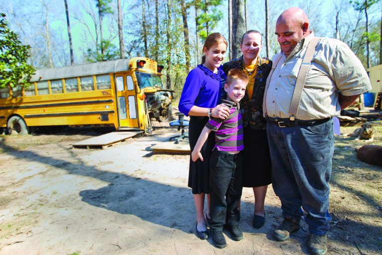 Sherrie, second right, and Mark Shorten, right, pose for photos with their children, 12, left, and Chance, 6, in front of their home, a converted school bus, in Splendora, Texas on Tuesday, Jan. 22, 2013. Nearly a year after their two children were found living virtually unsupervised in the old school bus, the Shortens regained full custody of their kids Tuesday when a judge dismissed a child welfare case against them. (AP Photo/Houston Chronicle, Karen Warren) MANDATORY CREDIT