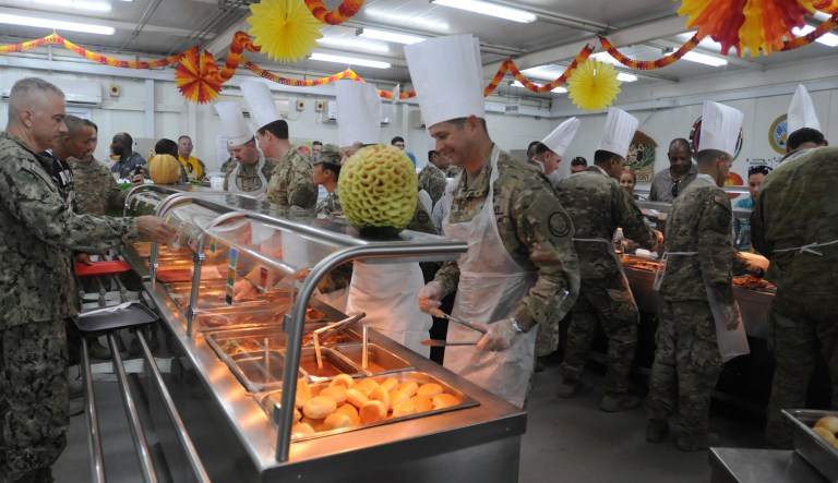 This photo released on Thursday, Nov. 23, 2017 by Combined Joint Task Force - Operation Inherent Resolve, the U.S-led effort against the Islamic State group, shows officers serving their soldiers Thanksgiving Day dinner in a dining facility at Camp Arifjan, Kuwait. (Tech. Sgt. Daniel Ter Haar, CJTF-OIR via AP )