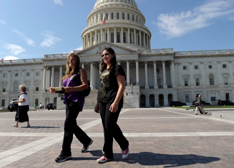   In this Oct. 1, 2013, photo, tourists Mary Avanti, left, and her granddaughter Galina, right, visit walk outside the U.S. Capitol in Washington. Tourists are pretty much locked out of Washington's monuments and museums, but those who want to hear lawmakers argue some more about the government shutdown are welcome to it. 