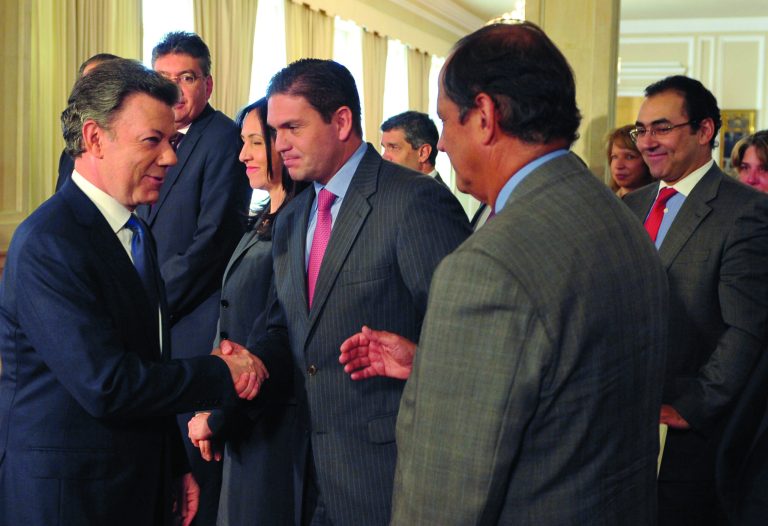 In this photo released by Colombia's Presidential Office, President Juan Manuel Santos, left, shakes hands with his Defense Minister Juan Carlos Pinzon as other cabinet ministers surround him after he announced the signing of a preliminary agreement to launch peace talks with the Revolutionary Armed Forces of Colombia, or FARC, a nationally televised speech from the presidential palace in Bogota, Tuesday, Sept. 4, 2011. Santos said the talks would begin in early October in Oslo, Norway, and would continue in Havana, Cuba. (AP Photo/Javier Casella, Colombia's Presidential Office)