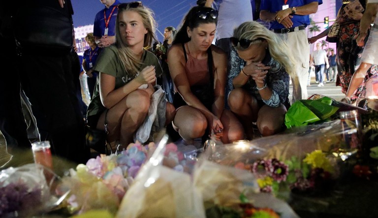 People pause at a memorial set up for victims of a mass shooting in Las Vegas, Nev., on Tuesday, Oct. 3, 2017. A gunman opened fire on an outdoor music concert on Sunday. It was the deadliest mass shooting in modern U.S. history, with dozens of people killed and hundreds injured, some by gunfire, some during the chaotic escape. (AP Photo/John Locher)