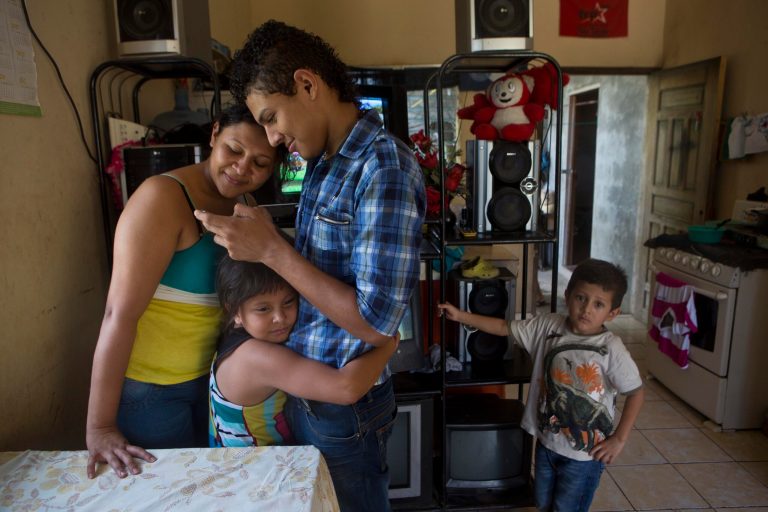 Eight-year-old Sandra holds onto to her uncle Pedro Ramirez, 18, earlier this month as he scrolls through a cellphone looking at photos with his sister Elsa Ramirez, 27, who was deported with her two children, Sandra and Cesar, right, from the United States a day earlier, in Tocoa, Honduras. Ramirez was one of 58 women and children who returned on a U.S. flight to San Pedro Sula. (AP Photo/Esteban Felix)