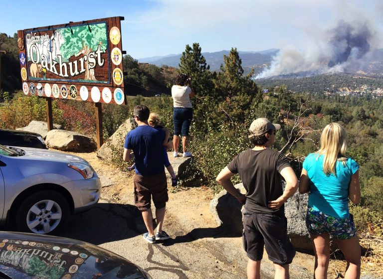People watch a fire burning from the Highway 41 overlook on the way north into Oakhurst, Calif., Monday, Aug. 18, 2014. The fire is burning north of the community. (AP Photo/The Fresno Bee, Eric Paul Zamora)