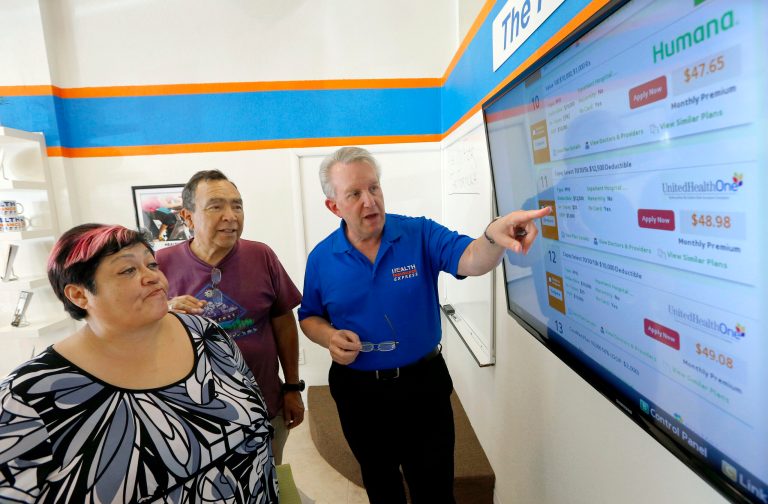 Alan Leafman explains specific health plans to Raquel Bernal, left, and her husband John Bernal, middle, both of Apache Junction, Ariz., as they navigate the nation's new health care insurance system online Oct. 1 in Mesa, Ariz. (AP Photo/Ross D. Franklin)