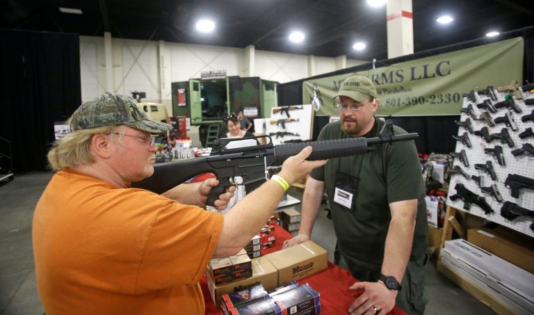 Beryl Paffrath, left, handles a Akdal 1919, AR-15 style, 12 gauge shotgun, while Matthew T. Kitterman, of MTK Arms, looks on during the PrepperCon expo Friday, April 24, 2015, in Sandy, Utah. Hundreds of survivalists and 