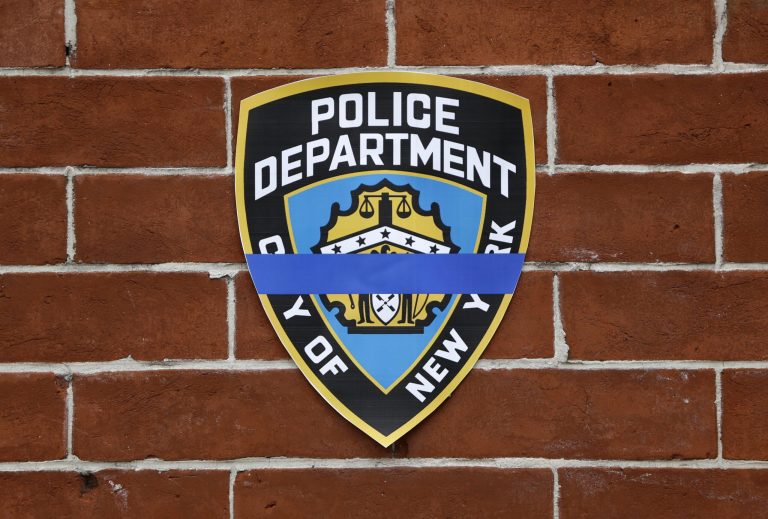 A police shield with a mourning band is displayed at a makeshift memorial near the site where New York City police officers Rafael Ramos and Wenjian Liu were murdered in the Brooklyn borough of New York, Monday. (AP/Seth Wenig)