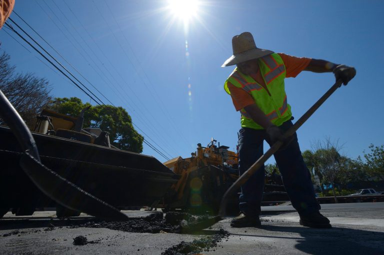 In this Monday, Sept. 15, 2014 photo, Marco Rencon shovels hot asphalt on a parking lot along Atlantic Avenue in Long Beach, Calif. Temperatures in Southern California have hit triple digits in many areas, sending Californians to their air conditioners and driving up power usage to its highest peak of the year. (AP Photo/The Orange County Register, Jeff Gritchen)