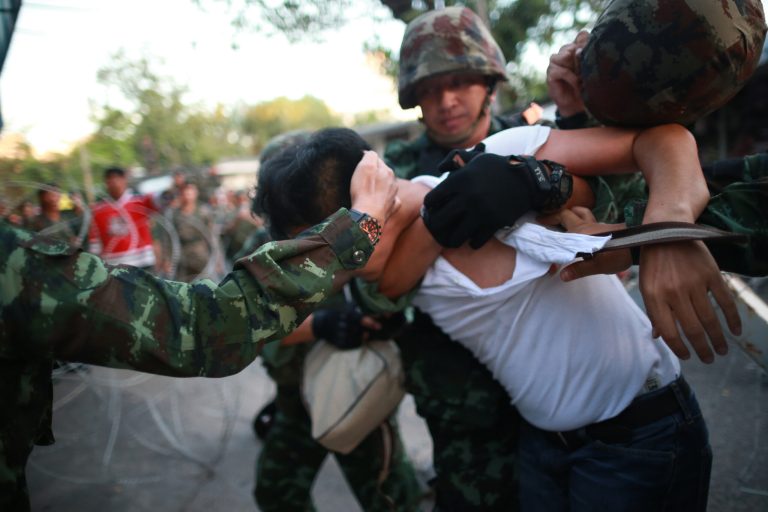 A protester is detained by Thai soldiers during an anti-coup demonstration at the Victory Monument in Bangkok, Thailand, Saturday, May 24, 2014. Thailand's coup leaders said Saturday that they would keep former Prime Minister Yingluck Shinawatra, Cabinet members and anti-government protest leaders detained for up to a week to give them 