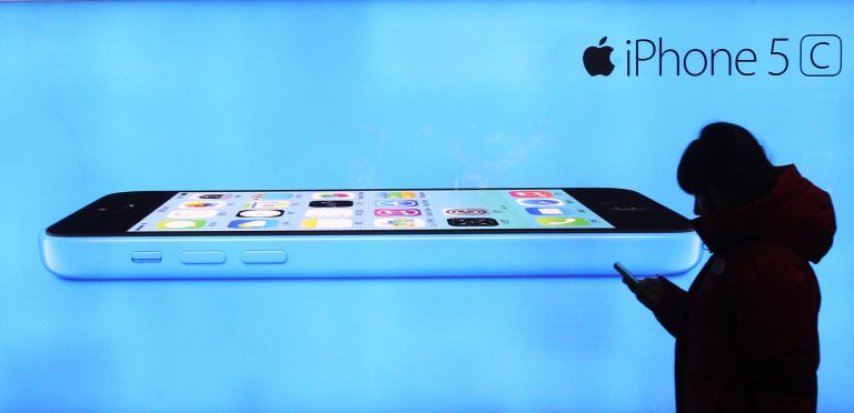 In this Dec. 12, 2013 file photo, a woman walks by a banner advertising iPhone 5C at a subway station in Seoul, South Korea. (AP Photo/Ahn Young-joon)