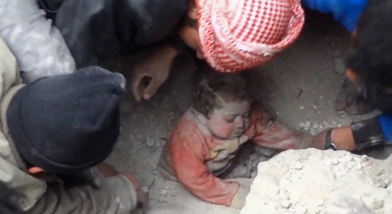 In this citizen journalism image made from Wednesday, Jan. 22, 2014 video provided by Nur Media Center, an anti-government activist group, which has been authenticated based on its contents and other AP reporting, men dig 14-month-old Ghina Khalil out of rubble in Aleppo, Syria. The chubby toddler was pulled out after men pulled aside rocks, concrete rubble and dust to free her, caught under a smashed building, bombed by the government forces in the area of Masaraniyeh in Aleppo. (AP Photo/Nour Media Center)