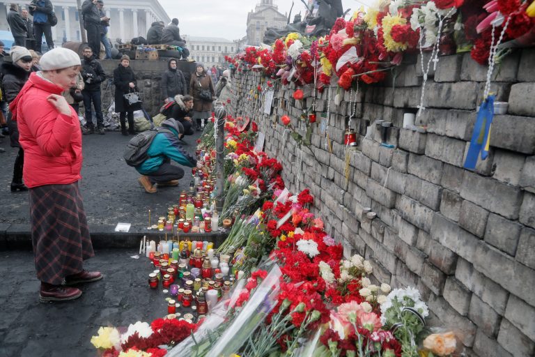 People lay flowers and lit candles at one of the barricades heading to Kiev's Independence Square, the epicenter of the country's recent unrest, Ukraine, on a mourning day Sunday, Feb. 23, 2014. (AP Photo/Efrem Lukatsky)