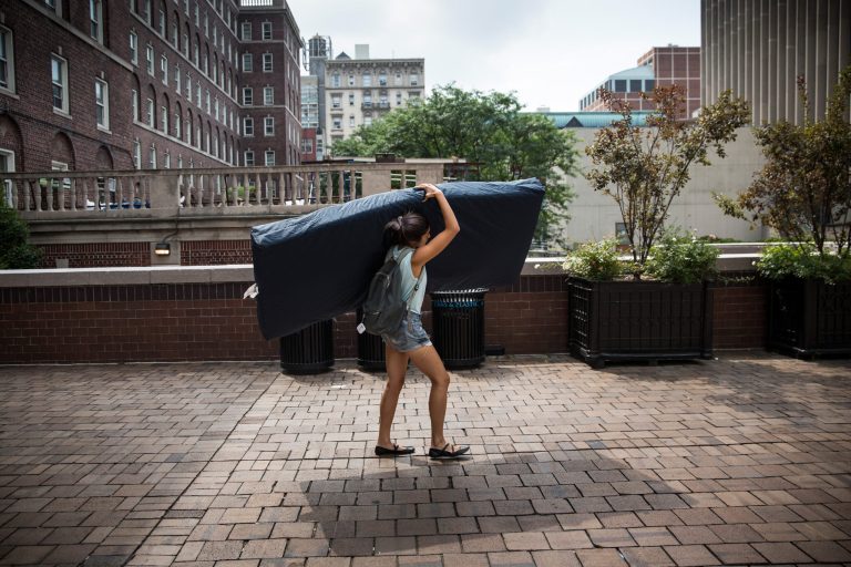 Emma Sulkowicz, carries a mattress in protest of the university's lack of action after she reported being raped. (Getty)