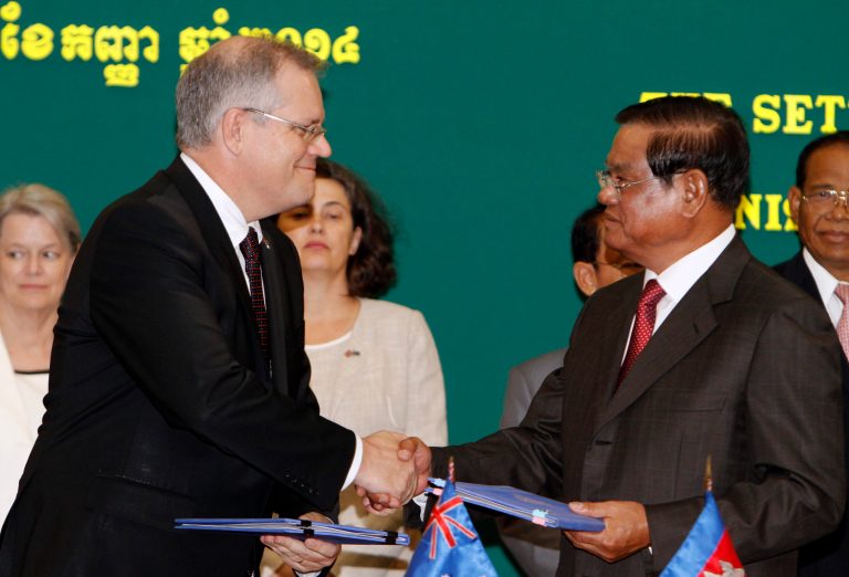 Australian Immigration Minister Scott Morrison, left, shakes hands with Cambodian Interior Minister Sar Kheng, right, after a signing ceremony of a controversial deal on resettlement of refugees inside the Interior Ministry in Phnom Penh, Cambodia, Friday, Sept. 26, 2014. Cambodia signed the deal with Australia to resettle an unspecified number of refugees currently held at an Australian-run detention camp on the tiny Pacific island nation of Nauru. About 100 people, including Buddhist monks, demonstrated outside Australia's embassy in Cambodia against the deal. (AP Photo/Heng Sinith)