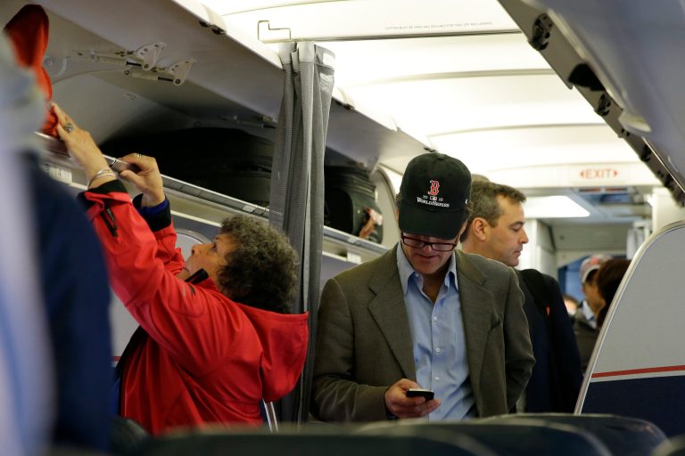 FILE - In this Thursday, Oct. 31, 2013 file photo, a passenger checks his cell phone while boarding a flight,  in Boston.  Allowing airline passengers to make cellphone calls in-flight is asking for trouble, lawmakers said Tuesday, Feb. 11, 2014, as a House panel approved a bill to ban such calls. (AP Photo/Matt Slocum)