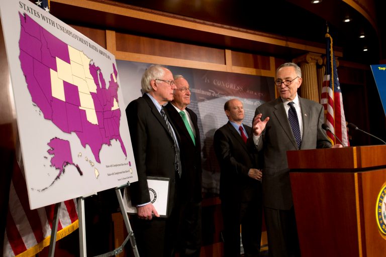   FILE- In this Dec. 6, 2012, photo, Sen. Charles Schumer, D-N.Y., right, accompanied by from left, Sen. Bernard Sanders, I-Vt., Sen. Tom Harkin, D-Iowa, and Sen. Chris Coons, D-Del., gestures during a news conference the possibility of Americans abruptly their jobless benefits at the of the year on Capitol Hill in Washington, Hovering in the background of the 