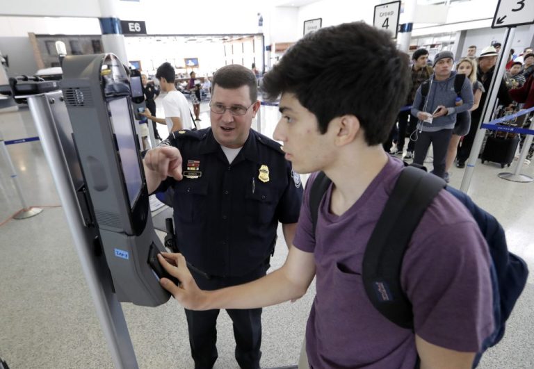 U.S. Customs and Border Protection supervisor Erik Gordon, left, helps passenger Ronan Pabhye navigate one of the new facial recognition kiosks at a United Airlines gate before boarding a flight to Tokyo on July 12, 2017, at George Bush Intercontinental Airport, in Houston. The Trump administration intends to require that American citizens boarding international flights submit to face scans, something Congress has not explicitly approved and privacy advocates consider an ill-advised step toward a surveillance state. (AP Photo/David J. Phillip)