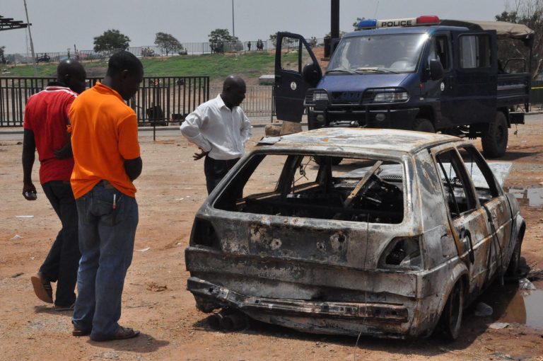 People inspect a damaged car following a bomb explosion in Abuja, Nigeria, Friday, May. 2, 2014. The death toll from a car bomb that exploded on a busy road in Nigeria's capital rose to more than a dozen overnight with dozens of people wounded, police said Friday from the city that within days hosts an international conference. The bomb was driven near a checkpoint where traffic built up, right across the road from a busy bus station where a massive explosion on April 14 killed dozens of people.  (AP Photo / Gbemiga Olamikan)