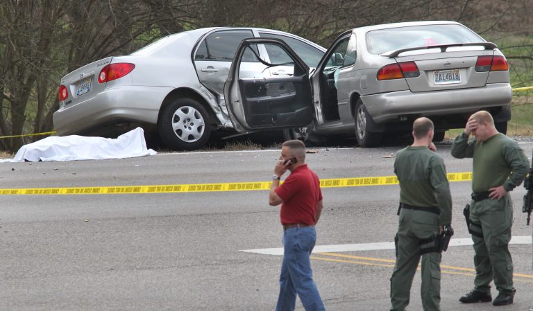  Authorities react as they stand watch over a scene where a body lies covered with a sheet on Hwy 78 in Oxford, Ala., Saturday, Dec. 15, 2012. Police officers in eastern Alabama shot an assailant armed with an AK-47 assault rifle toward the end of a pursuit that left several people injured, authorities said. The pursuit began after a shooting in Cleburne County. The county is near the Georgia state line. The person in the road was killed by police after leading them on a high speed chase after shooting several people. (AP Photo/Anniston Star, Stephen Gross)  