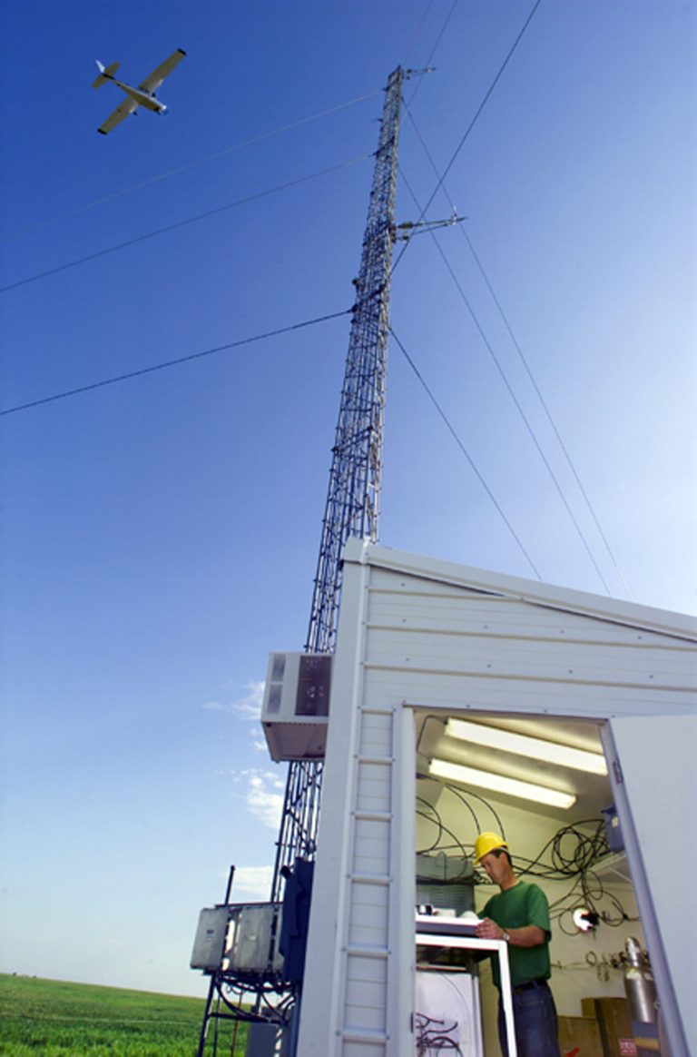 This undated handout photo provided by the Lawrence Berkeley National Laboratory/ Energy Department shows a Cessna plane, making continuous observations of carbon dioxide, flying over an Atmospheric Radiation Measurement tower used by the Energy Department near the town of Lamont, Oklahoma. Pat Dowell, a research technician at Lawrence Berkeley National Laboratory is collecting flask samples from the tower. America is spewing 50 percent more methane _ a potent heat-trapping gas _ than the federal government estimates, a new comprehensive scientific study said. And much of it is coming from just three energy-and-cow heavy states: Texas, Oklahoma and Kansas. (AP Photo/Roy Kaltschmidt, Lawrence Berkeley National Laboratory.)