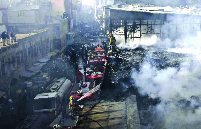 Afghan policemen and fire fighters investigate the scene of a burning market in Kabul, Afghanistan, Sunday, Dec. 23, 2012. Hundreds of shops at a market were burnt in a fire, but no causalities were reported. (AP Photo/Musadeq Sadeq)