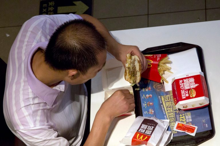 A man eats a burger at a McDonald's restaurant in Beijing Tuesday, July 22, 2014. China's food safety agency on Tuesday announced a nationwide inspection of processing factories and meat suppliers used by a company accused of selling expired beef and chicken to McDonald's and KFC. (AP Photo/Ng Han Guan)