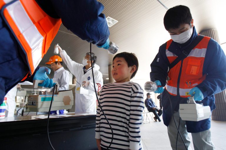   FILE - In this Friday, April 1, 2011 file photo, a boy is screened for radiation contamination before entering an evacuation center in Fukushima, Japan. Influential Japanese scientists who help set national radiation exposure limits have for years had trips paid for by the countryâs nuclear plant operators to attend overseas meetings of the worldâs top academic group on radiation safety. Some of these same scientists have consistently given optimistic assessments about the health risks of radiation, interviews with the scientists and government documents show. Their pivotal role in setting policy after the March 2011 tsunami and ensuing nuclear meltdowns meant the difference between schoolchildren playing outside or indoors and families staying or evacuating. (AP Photo/Wally Santana, File)  