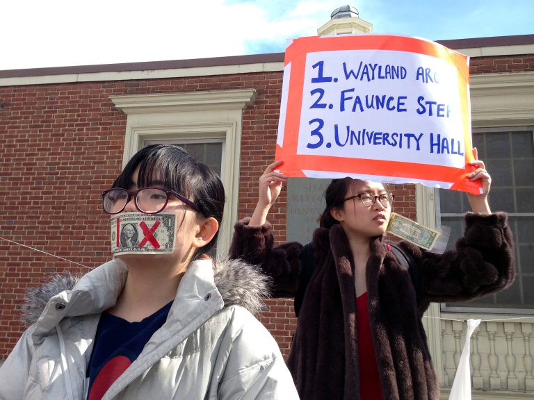Brown University students Pei Ling Chia of Singapore, left, and Nicha Ratana of Bangkok, Thailand, right, stand on campus as students gather Wednesday, March 11, 2015, in Providence, R.I., to protest the school's handling of recent sexual assault cases. (AP Photo/Amy Anthony)
