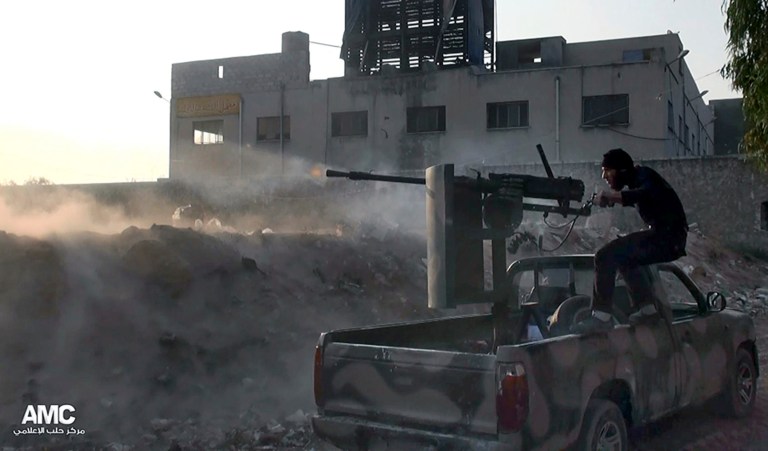 FILE - In this Saturday, Nov. 9, 2013 file citizen journalism image provided by Aleppo Media Center AMC, which has been authenticated based on its contents and other AP reporting, a Syrian rebel fires a weapon towards Syrian government troops loyal to President Bashar Assad in Aleppo, Syria. Syria's government and opposition will hold their first peace talks on Jan. 22 in Geneva, in an attempt to halt the nearly 3-year-old civil war that has killed more than 100,000 people, the United Nations announces. (AP Photo/Aleppo Media Center AMC, File)