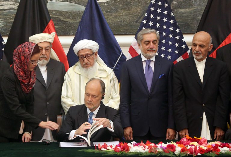U.S. Ambassador to James Cunningham, seated, signs the documents of the Bilateral Security Agreement (BSA) at the presidential palace as Afghanistan's president Ashraf Ghani Ahmadzai, first right, and chief executive Abdullah Abdullah, second right, watch, in Kabul, Afghanistan, Tuesday, Sept. 30, 2014. Afghanistan and the United States signed a long-awaited security pact on Tuesday that will allow U.S. forces to remain in the country past the end of year. (AP Photo/Massoud Hossaini)