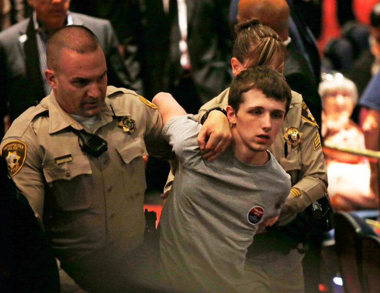 Police remove Michael Sandford as Republican presidential candidate Donald Trump speaks in July at the Treasure Island hotel and casino in Las Vegas. (AP Photo/John Locher)