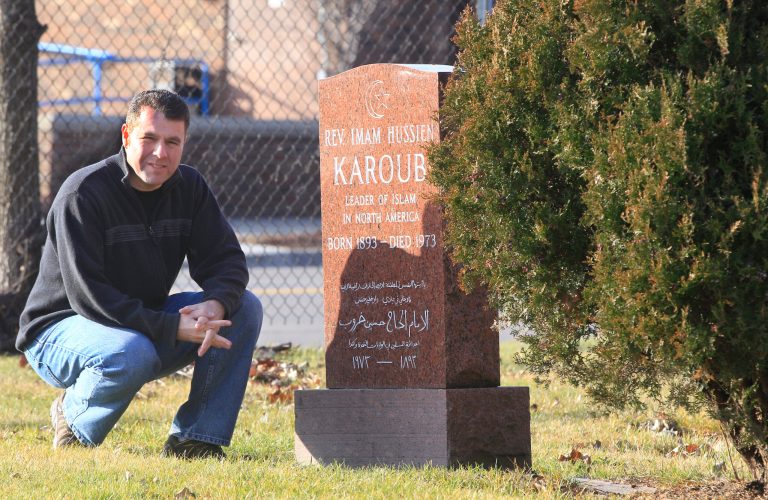   ADVANCE FOR USE SUNDAY, DEC. 30, 2012 AND THEREAFTER - This Dec. 18, 2012 photo shows Detroit Associated Press reporter Jeff Karoub next to the tombstone of his grandfather, The Rev. Imam Hussien Karoub, in Berkley, Mich. Wanting to fill some ancestral gaps, Jeff is piecing together the story of his grandfather who immigrated to America in 1912. (AP Photo/Carlos Osorio)  