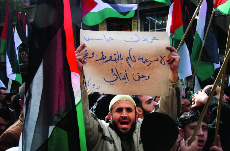 FILE - In this Friday, Jan. 28, 2011 file photo, a Palestinian man shouts slogans as he carries a banner that reads in Arabic, 