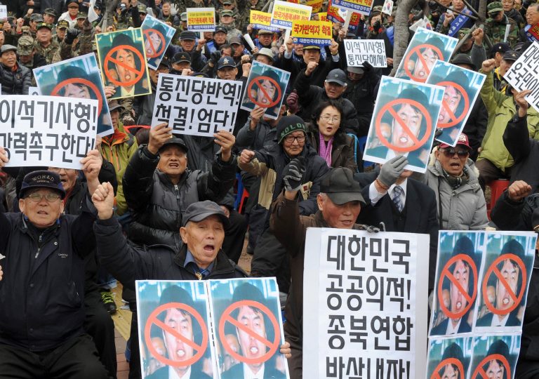 Conservative activists hold defaced photos of leftwing lawmaker Lee Seok-ki of the Unified Progressive Party while shouting slogans during a rally against Lee in front of the Suwon District Court in Suwon, South Korea, Monday, Feb. 17, 2014. The court on Monday sentenced Lee to 12 years in prison for plotting a pro-North Korea rebellion in the event of a war on the Korean Peninsula. The placards held by the protesters read: 