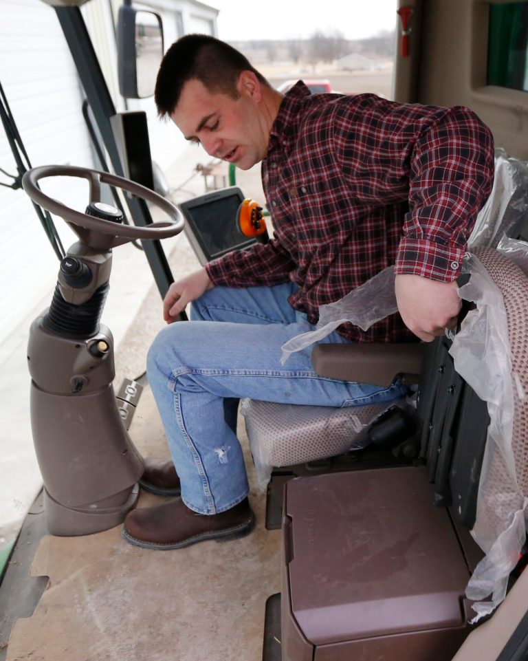 Nick Guetterman folds a seat as he climbs into a combine on his farm near Bucyrus, Kan., Wednesday, Feb. 19, 2014.  Farmers from across the nation gathered in Washington this month for their annual trek to seek action on the most important matters in American agriculture.  But this time, a new issue emerged: growing unease about how the largest seed companies are gathering vast amount of data from sensors on tractors, combines and other farm equipment. The sensors measure soil conditions, seeding rates, crop yields and many other variables.  (AP Photo/Orlin Wagner)