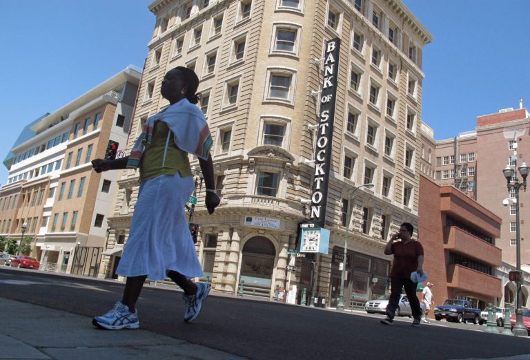 FILE  - In this June 27, 2012 file photo, pedestrians cross a street near the Bank of Stockton in Stockton, Calif.  A federal judge could rule Wednesday, Oct. 1, 2014, on a bankruptcy exit plan for Stockton, an inland port city in California that in 2012 became the largest city in the U.S. to file for Chapter 9 protection before Detroit filed last year. U.S. Bankruptcy Judge Christopher Klein has scheduled a hearing in Sacramento in a trial that has lasted more than four months. (AP Photo/Gosia Wozniacka, File)