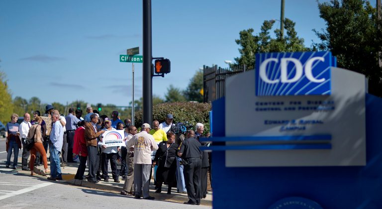 Protestors demonstrate against the government shutdown outside the Centers for Disease Control and Prevention, Tuesday, Oct. 8, 2013, in Atlanta. About two dozen people protested outside the CDC on Tuesday afternoon, trying to cast a harsh spotlight on the temporary federal shutdown. The small group called on Congress to vote on a measure that would restart federal funding. (AP Photo/David Goldman)