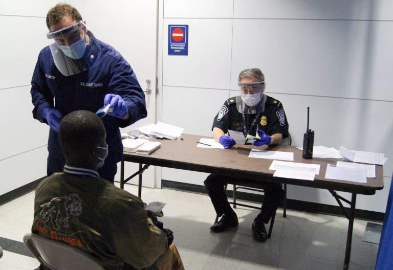 FILE- In this Thursday, Oct. 16, 2014, file photo released by U.S. Customs and Border Protection, U.S. Coast Guard Health Technician Nathan Wallenmeyer, left, and CBP supervisor Sam Ko, right, conduct prescreening measures on a passenger who has arrived from Sierra Leone at O'Hare International Airport's Terminal 5 in Chicago. Demands are rising in Washington for the U.S. to ban travelers from countries in West Africa, but the Obama administration is resisting and says the screening measures already in place for travelers are more effective. (AP Photo/U.S. Customs and Border Protection, Melissa Maraj, File)