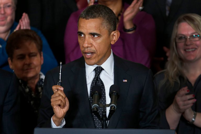 President Obama holds up a pen as he speaks. (AP/Carolyn Kaster)