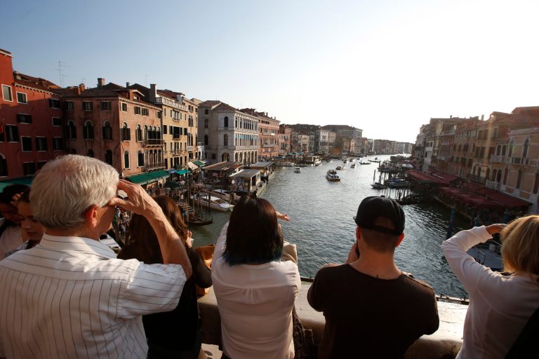 Tourists enjoy the view from the Rialto bridge in Venice, Italy, Thursday, Sept. 25, 2014. Venice city officials are closing a walkway fronting the picturesque Grand Canal on Monday to keep crowds away from George Clooney's wedding to human rights lawyer Amal Alamuddin. The city on Thursday issued an order closing walkways accessing the 16th Century Cavalli Palace for at least two hours Monday, citing 