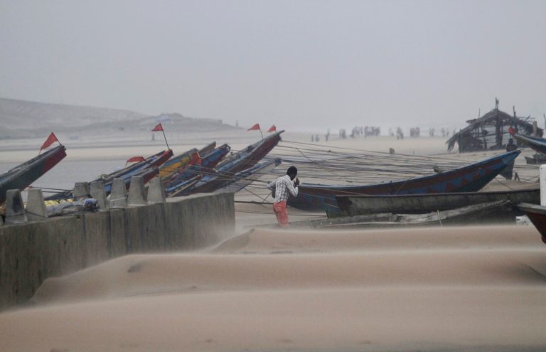 An Indian fisherman walks near the anchored fishing boats as strong winds blow a day after a powerful cyclone pounded the Bay of Bengal coast in Gopalpur, Orissa, about 285 kilometers (178 miles) north east of Visakhapatnam, India, Monday, Oct. 13, 2014. Cyclone Hudhud that slammed into India's eastern seaboard weakened as it moved inland Monday. (AP Photo/Biswaranjan Rout)