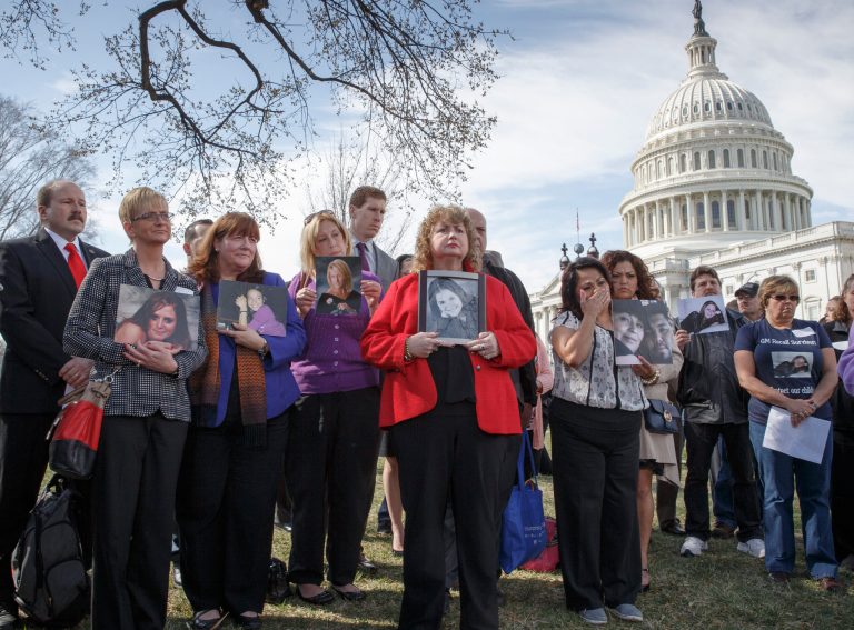 FILE - In this Tuesday, April 1, 2014, file photo families of victims of a General Motors safety defects in small cars hold photos of their loved ones as they gather on the lawn on Capitol Hill in Washington. Families of those who died in General Motors cars with defective ignition switches want prosecutors to go after GM insiders responsible for letting the problems fester for more than decade, and perhaps for covering them up. (AP Photo/J. Scott Applewhite, File)