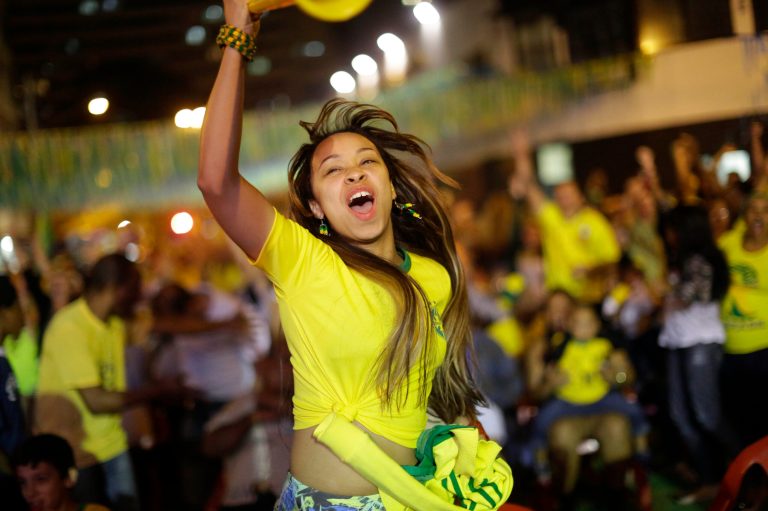 A Brazilian soccer fan celebrates after Brazil scored against Cameroon while watching the match on a giant television screen in Bixiga neighborhood in Sao Paulo, Brazil, Monday, June 23, 2014. Brazil's Neymar scored twice in the first half to lead Brazil to a 4-1 win over Cameroon on Monday, helping the hosts secure a spot in the second round of the soccer World Cup. (AP Photo/Nelson Antoine)