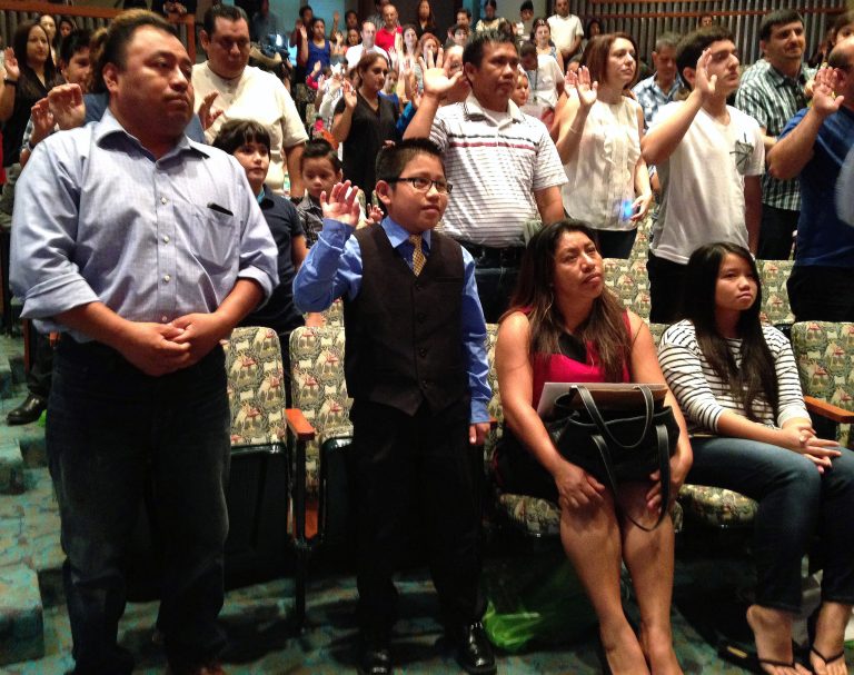Luis Litez, 10, center, from Oaxaca, Mexico repeats the Oath of Allegiance accompanied by his father Lamberto Litez, left and his mother second from the right, on Thursday, Sept. 18, 2014, during a citizenship ceremony at the Los Angeles Public Library, in downtown Los Angeles. (AP Photo/Edwin Tamara)