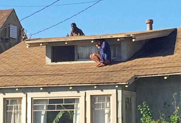 FILE - In this Wednesday, Sept. 24, 2014 file photo, Melora Rivera, who fled her house through an attic window to escape an intruder, seen on the roof behind her, waits for help after an early-morning break-in at her house in the Venice neighborhood of Los Angeles. The intruder, later identified as Christian Hicks, was arrested by Los Angeles police officers, Friday, Sept. 26, 2014. ( AP Photo/Venice311.org, Alex Thompson, File)