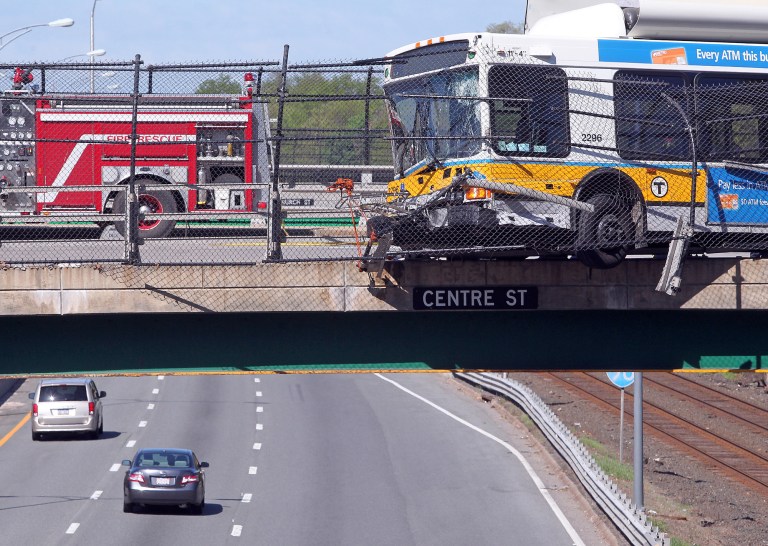 A Massachusetts Bay Transportation Authority bus hangs over the Massachusetts Turnpike after crashing on Centre Street in Newton, Mass., Sunday, May 18, 2014. Seven passengers and the bus driver were transported to a hospital with non-life-threatening injuries, MBTA spokeswoman Kelly Smith. Three other passengers declined medical treatment. (AP Photo/Boston Herald, Matt Stone)